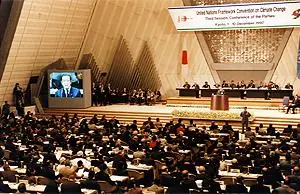 O primeiro-ministro japonês Ryutaro Hashimoto discursa no plenário da COP 3, em Quioto, em 3/12/1997 (foto do dia; arquivo pequeno, 300 × 194 px, só serve em tamanho reduzido)