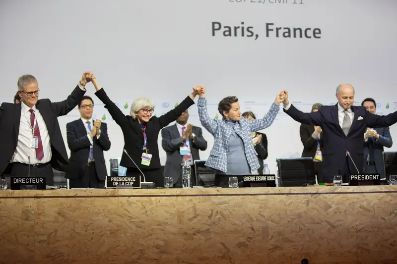 A mesa da COP21 de mãos dadas e erguidas logo após a adoção do Acordo de Paris, 12/12/2015.