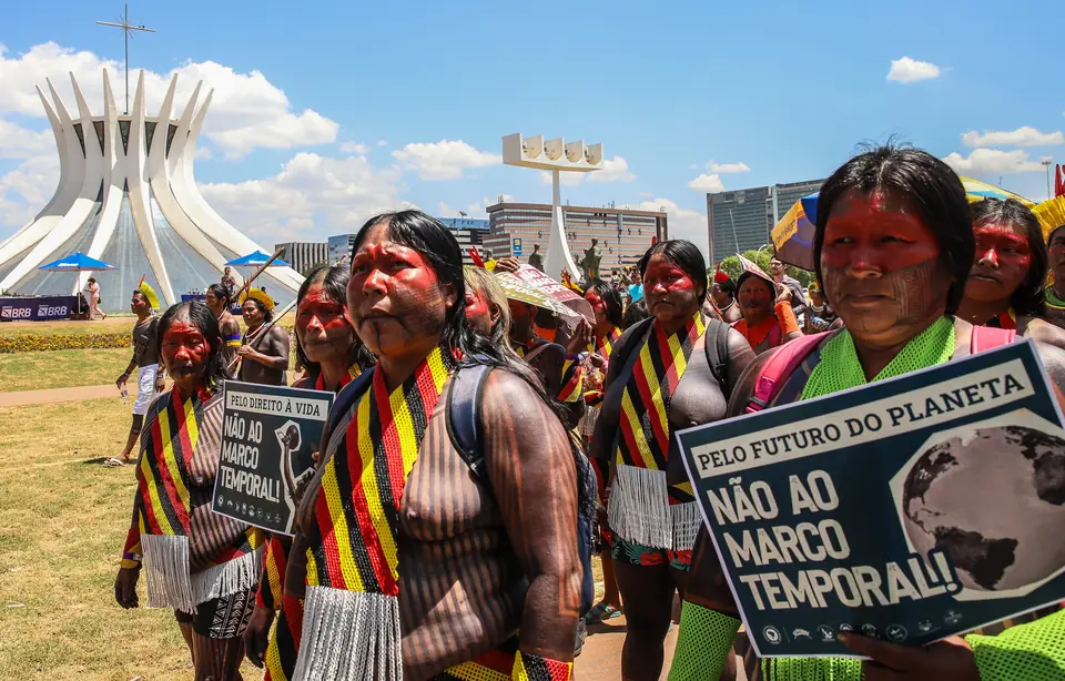 Indígenas marcham em Brasília com cartazes “Não ao marco temporal”, com a Catedral ao fundo (foto de arquivo usada pela Agência Brasil em 2026)